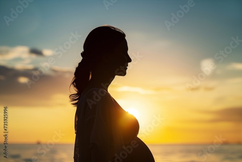 profile shot of a pregnant woman silhouetted against a sunset photo