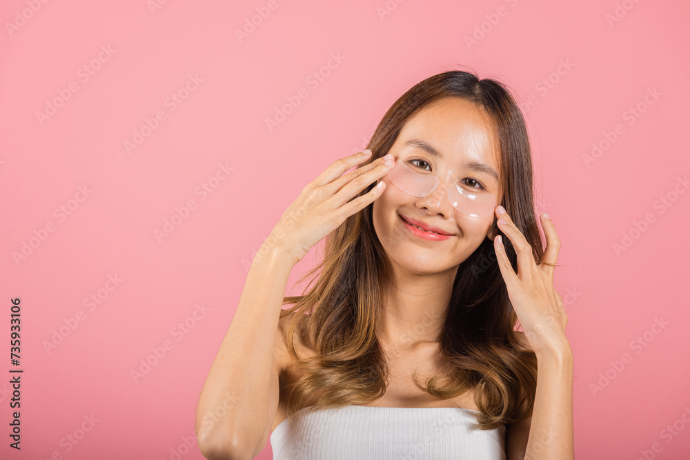 Femininity. Asian beautiful young woman smiling mask cosmetic patches gel under the eyes, Portrait female touching clean skin medical hydrogel eye patch on face, isolated on pink background, skincare Femininity. Asian beautiful young woman smiling mask cosmetic patches gel under the eyes, Portrait female touching clean skin medical hydrogel eye patch on face, isolated on pink background, skincare