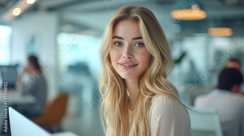 A cute blonde young woman working at desk in office with glass partitions. Generative AI.