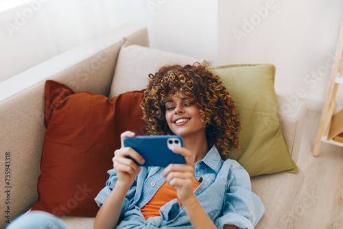 Just Chillin' on the Sofa: A Happy Woman Holding Her Phone at Home photo