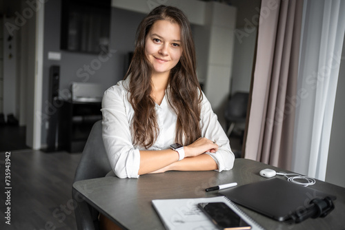 Portrait of smiling young business woman with laptop in home workplace, home office, home studying or teaching concept
