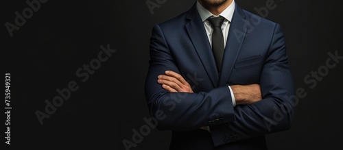 Confident businessman in elegant suit and tie standing with arms crossed
