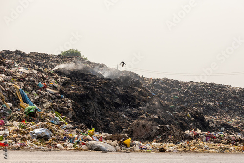 Piles of household waste are left on the side of the road. Dumping garbage in this way is polluting the environment. Some garbage is being burnt. photo