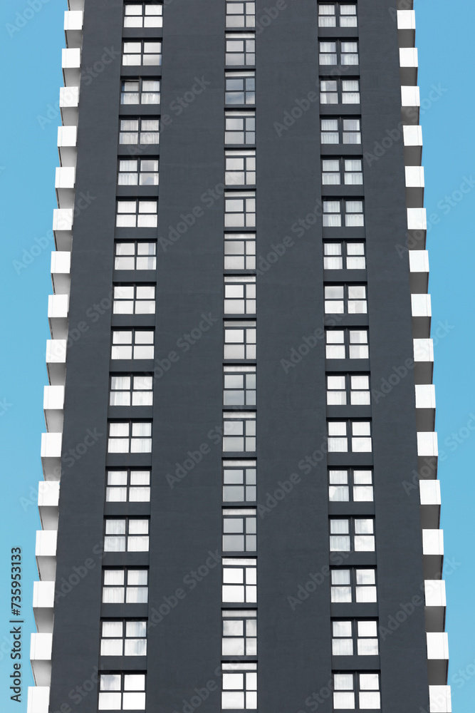 Fragment of a modern skyscraper stands tall against a clear blue sky