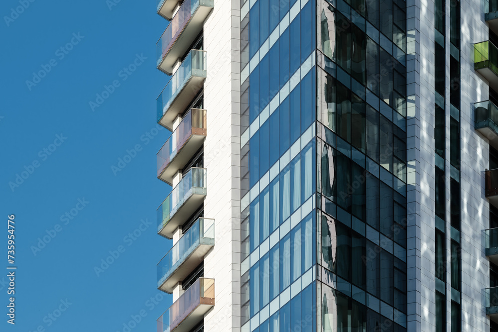 Detail of a modern residential building made of glass, steel and concrete against a clear blue sky.