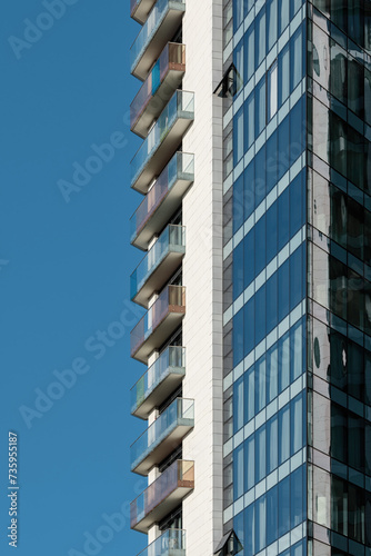 Detail of a modern residential building made of glass, steel and concrete against a clear blue sky