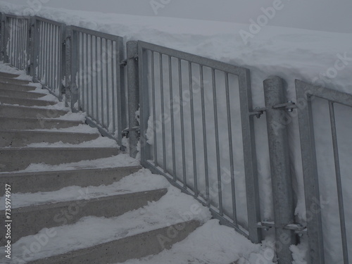 Stair covered in snow with stair handrail