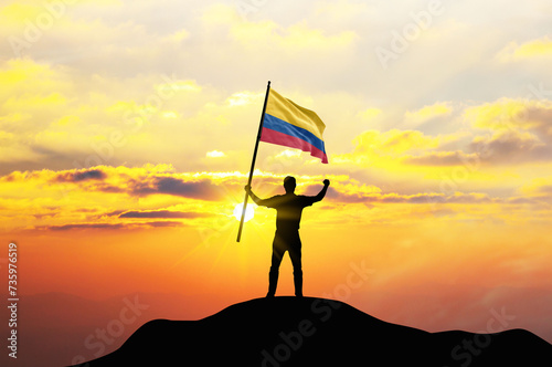 Colombia flag being waved by a man celebrating success at the top of a mountain against sunset or sunrise. Colombia flag for Independence Day. ©  minionionniloy