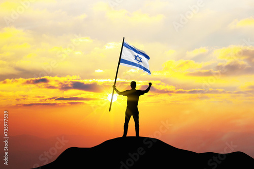 Israel flag being waved by a man celebrating success at the top of a mountain against sunset or sunrise. Israel flag for Independence Day. ©  minionionniloy
