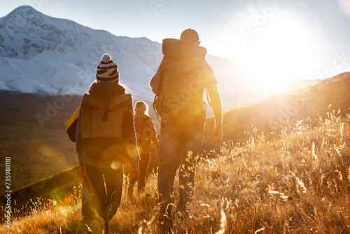 Group of hikers tourists with backpacks walks in sunset mountains. Active lifestyle concept