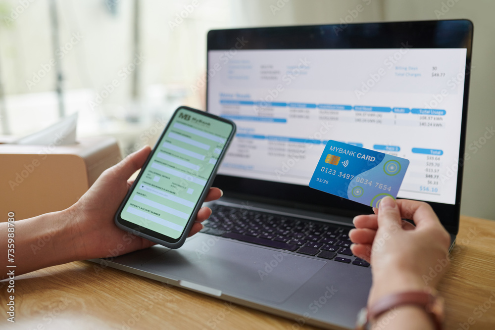 Woman entering information from credit card when paying utility bills online Woman entering information from credit card when paying utility bills online