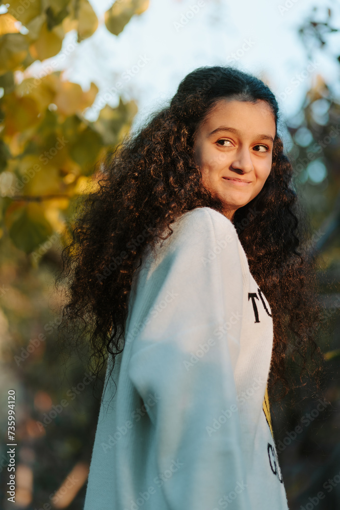 Portrait of 13 years old girl full of emotions smiling and looking at sunset through the sunrays