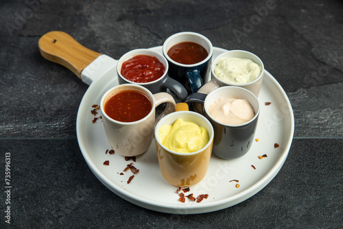 Variety of souces on white plate on dark background photo