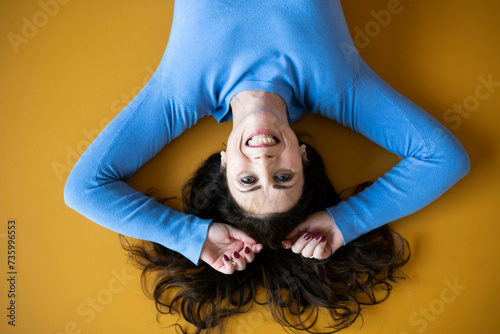 Attractive woman laying down with her hands above her head, her hair sprayed out and looking happy laughing photo
