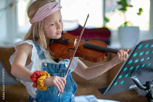 Young teenage girl playing violin, practising her new music. photo