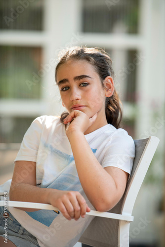 Young girl sitting on a chair in her garden upset photo