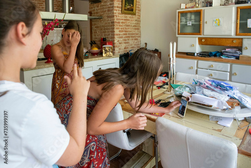 Young girls using their phone to record selfie videos dancing in their home for social media platform photo