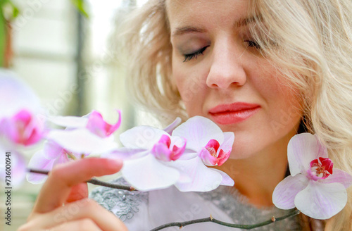 A woman's face is close to a pink archidea. The scent of flowers. Femininity concept photo