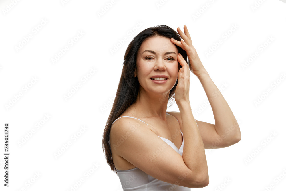 Portrait of 40s years old Caucasian woman in white top touching forehead and smiling against white studio background. Concept of beauty and fashion, spa treatments, self care, body care, wellness. Ad Portrait of 40s years old Caucasian woman in white top touching forehead and smiling against white studio background. Concept of beauty and fashion, spa treatments, self care, body care, wellness. Ad