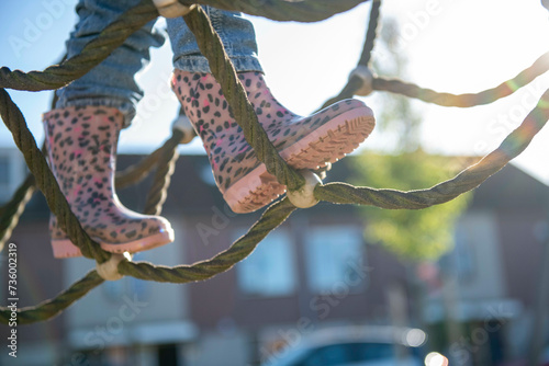Little girl being brave climbing through a adventure playground in public park photo