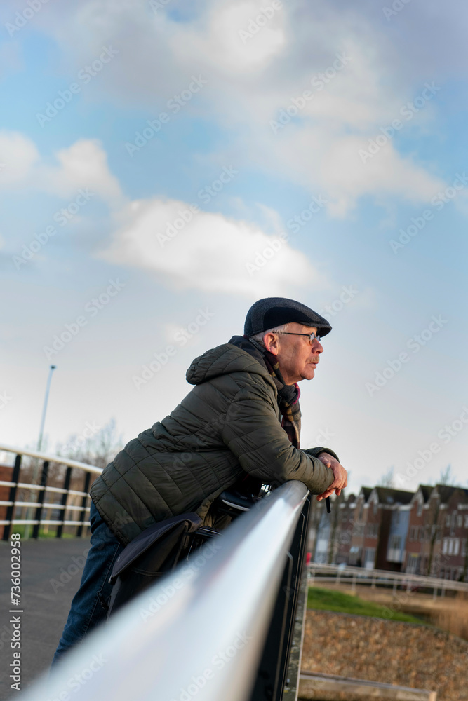 Elderly man going for a healthy walk and leaning on a railing looking at the landscape Elderly man going for a healthy walk and leaning on a railing looking at the landscape