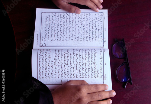 A boy read an Urdu historical book of Islam. urdu manuscript book study concept. book with glass educational concept. photo