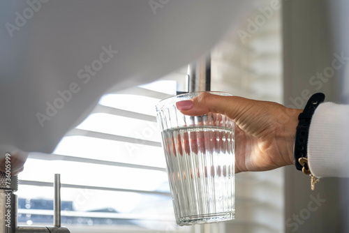 Lady filling her glass with fresh clean water photo