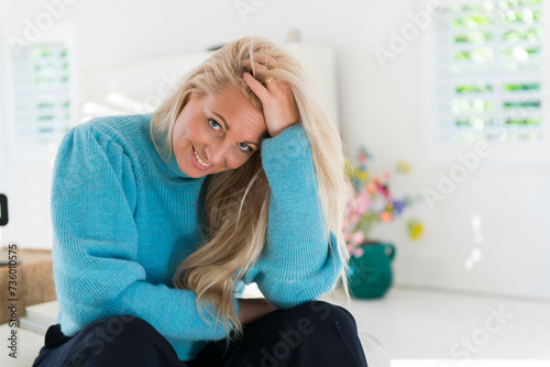 very attractive older blonde woman looking into camera for a portrait in her home looking very happy photo
