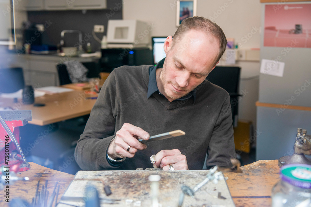 Looking into a workshop, Watch maker repairing a classic watch, authentic work place. Using a monocle and small tiny tools for repairs Looking into a workshop, Watch maker repairing a classic watch, authentic work place. Using a monocle and small tiny tools for repairs