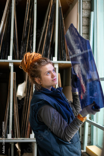 Female stained glass apprentice inspecting blue glass in the workshop