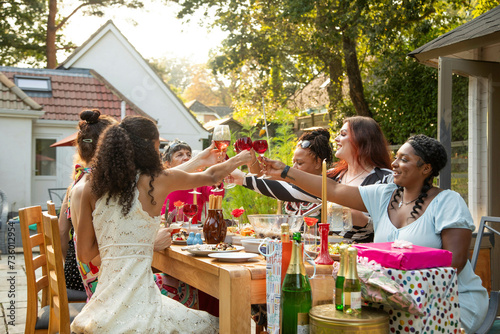 A mixed gathering of women laughing and having fun at a summer garden birthday party celebration lunch