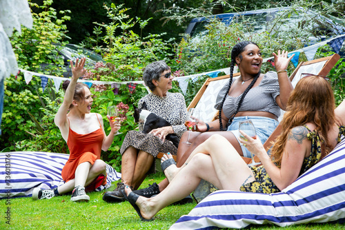 Mixed group of female friends and family gathering to have fun and  enjoy a summer BBQ garden party .