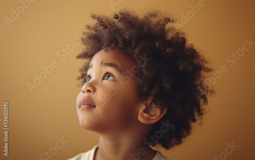 A multiracial little girl with curly hair looks up, showcasing her natural beauty and curious expression.