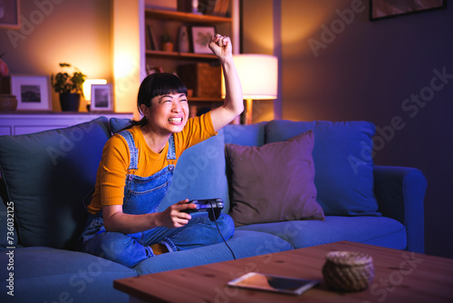 Woman playing video games at home celebrating after winning
