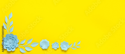 Beautiful paper flowers and leaves on yellow background with space for text