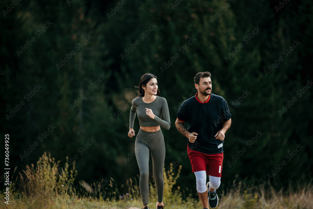 Fototapeta premium Active couple running together in the mountain wilderness, surrounded by tall pine trees
