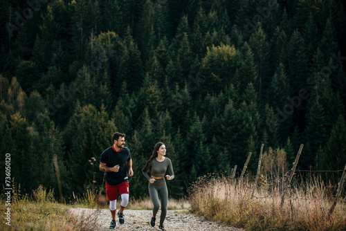 Fit diverse couple jogging amidst a scenic mountain landscape