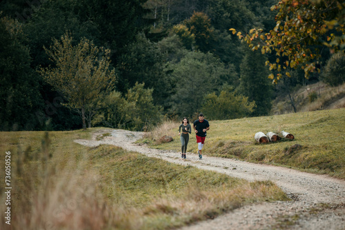 Diverse couple in matching fitness attire jogging together along a scenic mountain road