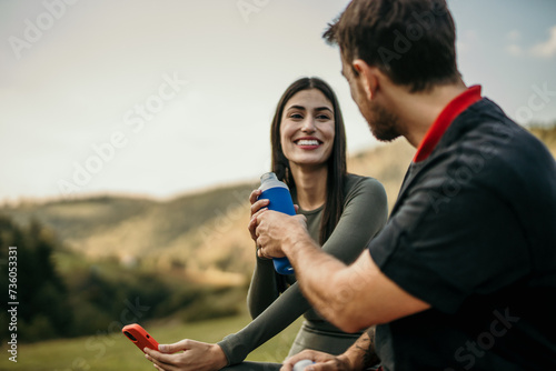 Multicultural friends take a breather after jogging, discussing their workout and drinking a water photo