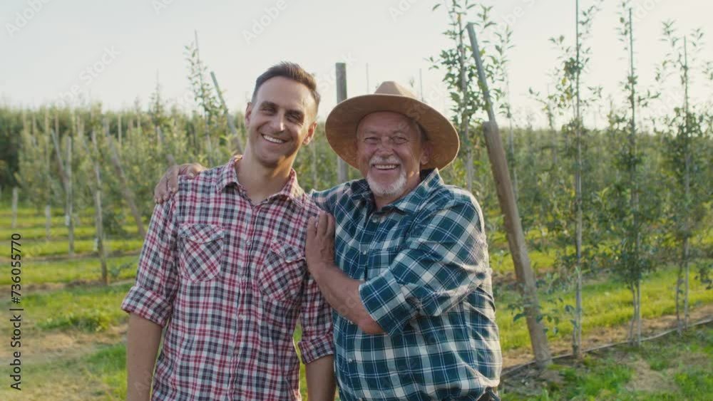 Portrait of mature father and his son on apple orchard Portrait of mature father and his son on apple orchard