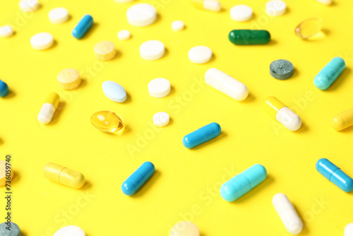 Fish oil capsules and different pills on yellow background