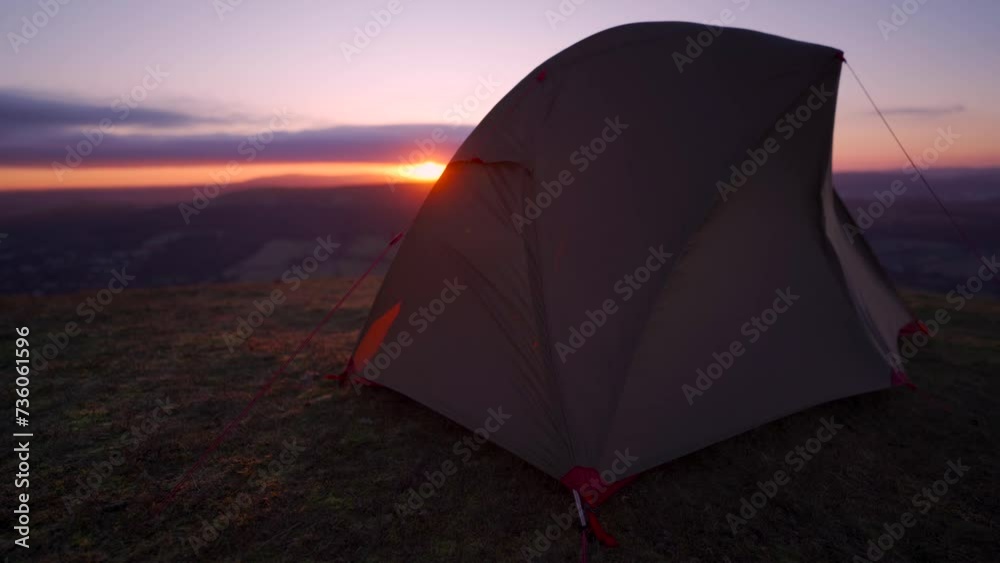 A wild camping blowing around in strong wind on a mountain summit at sunrise in England A wild camping blowing around in strong wind on a mountain summit at sunrise in England