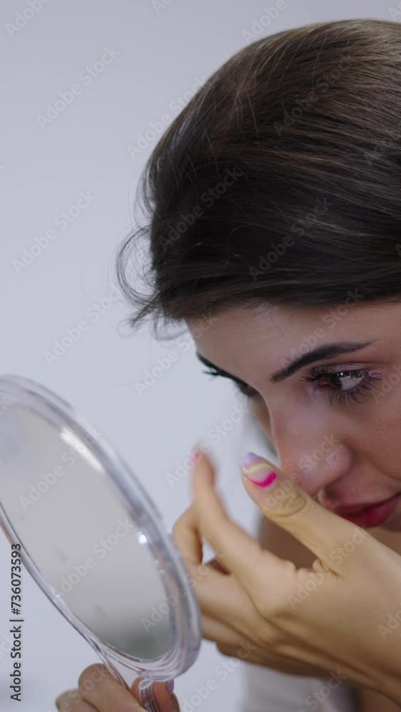 A brunette girl looks in the mirror after her hyaluronic acid treatment A brunette girl looks in the mirror after her hyaluronic acid treatment