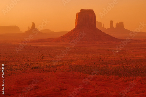 Windy, hazy sunset bathing the buttes and mesas of Monument Valley Navajo Tribal Park from the Artist's Point viewpoint, Arizona, USA.