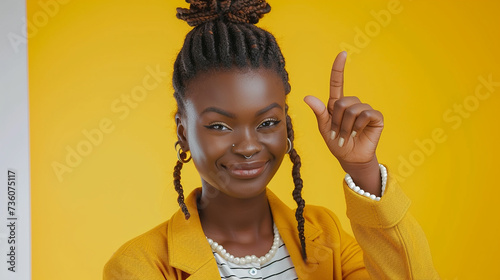  Retrato de estúdio de uma jovem mulher confiante posando sobre um fundo amarelo colorido brilhante, piscando e segurando o polegar para cima,