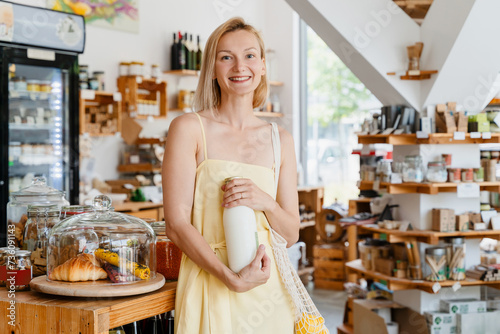 Smiling woman buying organic food and eco products in sustainable plastic free store. Happy female customer shopping at local grocery shop.