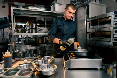 the chef stands in the kitchen of the establishment and gets ready to pour oil into frying pan