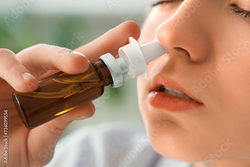 Ill young businesswoman using nasal drops in office, closeup