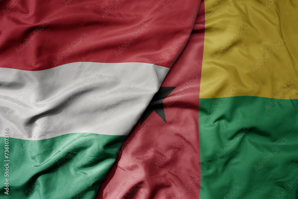 big waving national colorful flag of guinea bissau and national flag of hungary .