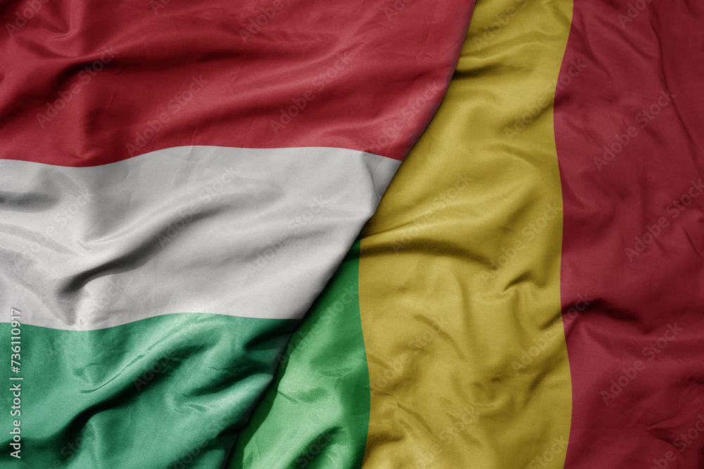 big waving national colorful flag of mali and national flag of hungary .